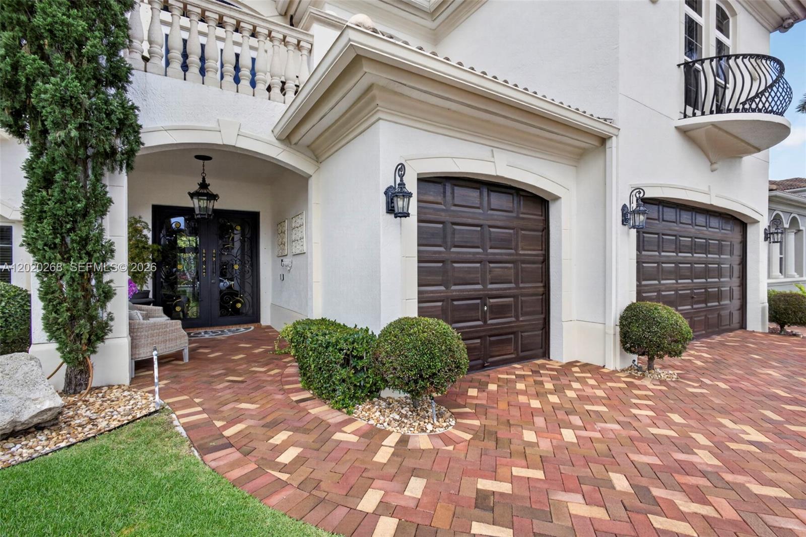 The exterior of a house features a brick driveway, two garage doors, and a covered entryway — 111 Abondance Dr, Palm Beach Gardens FL 33410, PALM BEACH GARDENS, FL