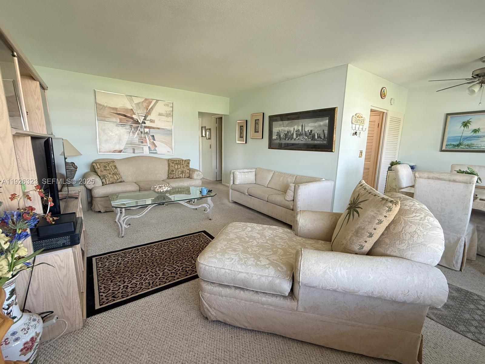A living room features light-colored sofas, a glass coffee table, and a patterned area rug — 90 Easthampton D # 90, West Palm Beach FL 33417, WEST PALM BEACH, FL