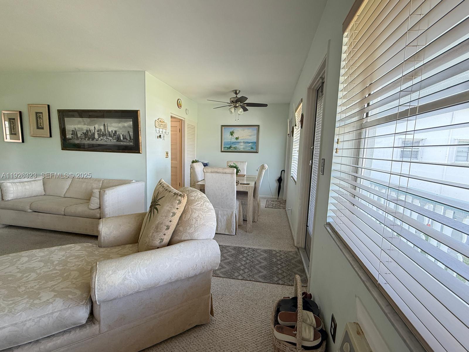 A living room and dining area feature light-colored furniture, carpeted floors, and a ceiling fan — 90 Easthampton D # 90, West Palm Beach FL 33417, WEST PALM BEACH, FL