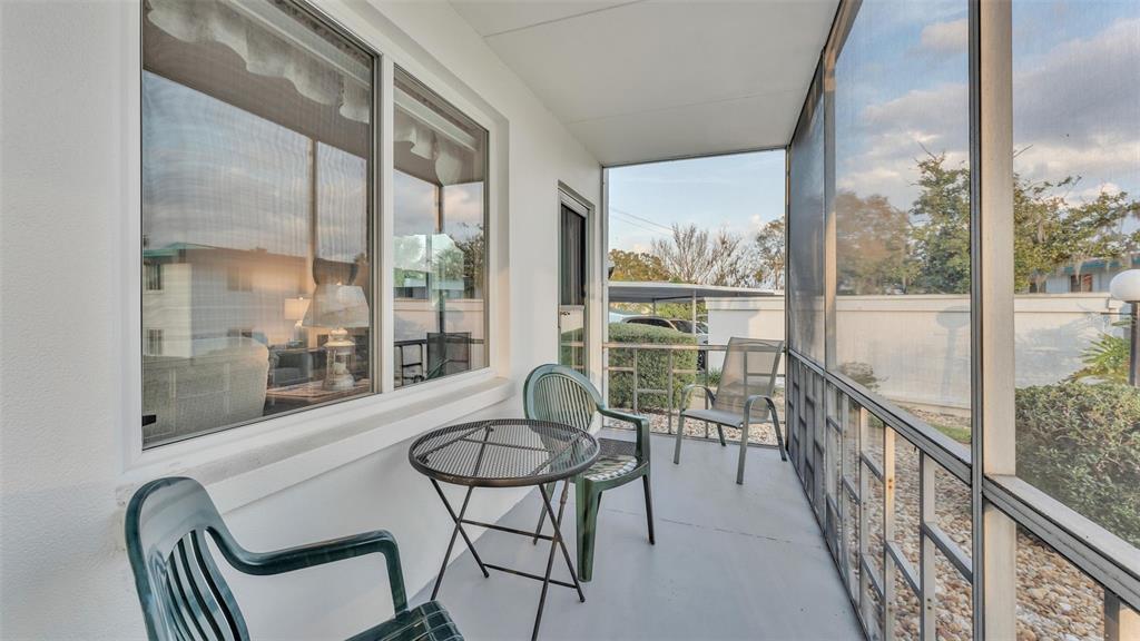 A screened-in porch features a small metal table, three chairs, and large windows — 1600 W LAKE PARKER DRIVE UNIT B9, LAKELAND, FL