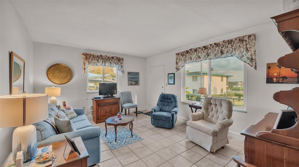A living room features tile flooring, a blue sofa, several armchairs, and two large windows — 1600 W LAKE PARKER DRIVE UNIT B9, LAKELAND, FL