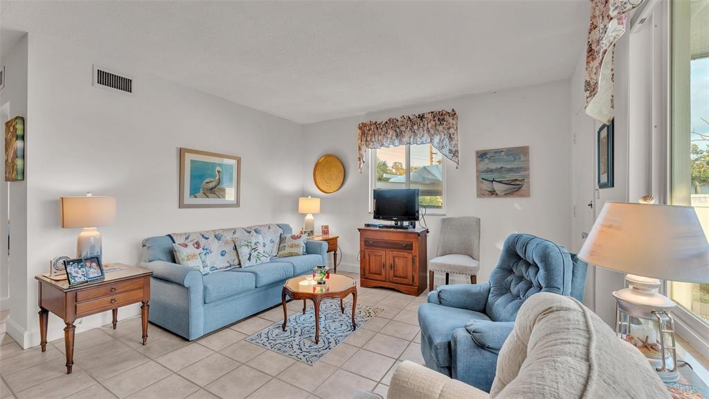 A living room features a blue sofa, a matching armchair, tile flooring, and a television — 1600 W LAKE PARKER DRIVE UNIT B9, LAKELAND, FL
