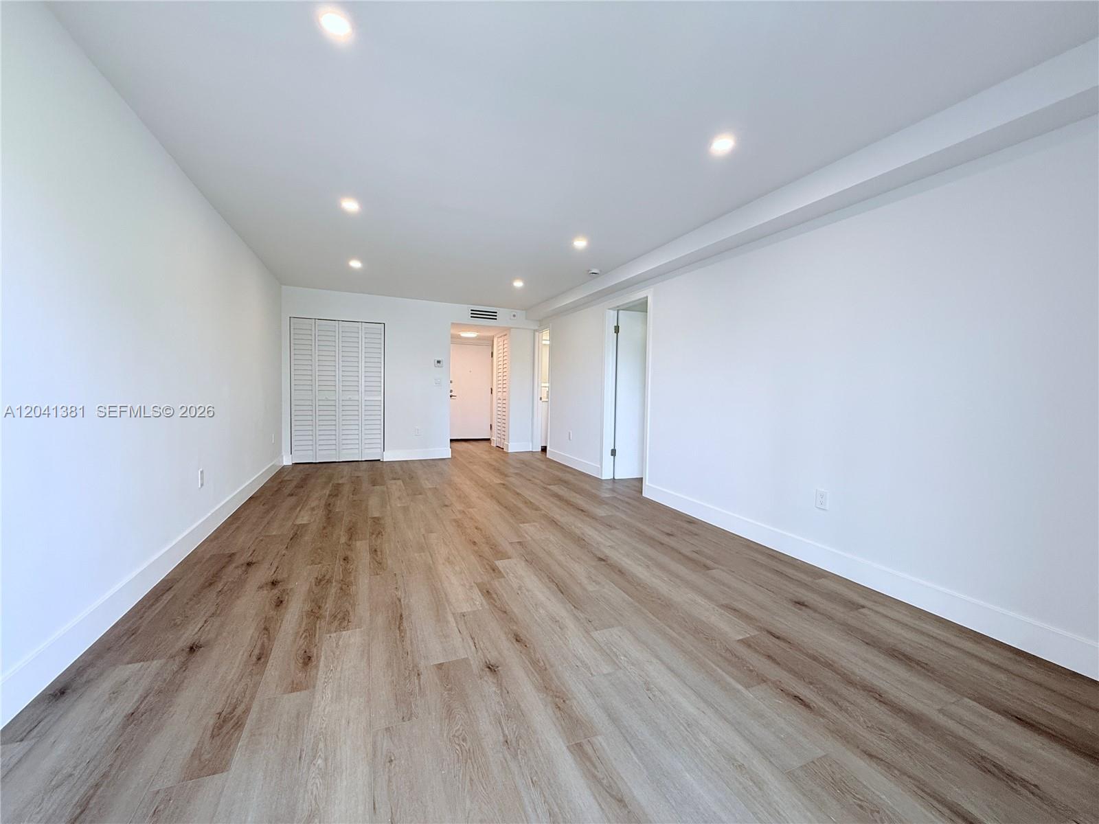 An empty room features white walls, recessed lighting, and light-toned wood-look flooring — 1900 Meridian Ave # 403, Miami Beach FL 33139, MIAMI BEACH, FL