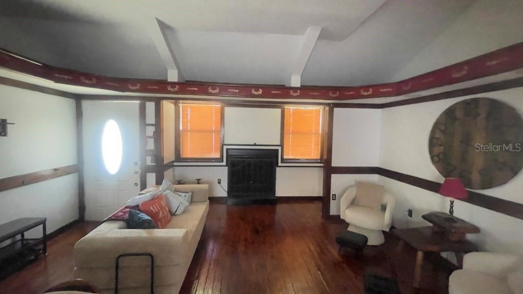 A living room features a fireplace, hardwood floors, a vaulted ceiling, and wood trim — 214 NE 4TH STREET, CHIEFLAND, FL