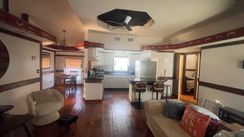 An open-concept living area features a kitchen with white cabinets, dark countertops, and wood flooring — 214 NE 4TH STREET, CHIEFLAND, FL