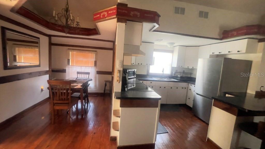 A kitchen with white cabinets and stainless steel appliances opens to a dining area — 214 NE 4TH STREET, CHIEFLAND, FL