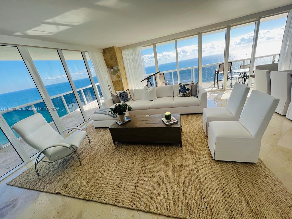 A bright living room features a white sofa, chairs, and floor-to-ceiling windows overlooking the ocean — 1830 S Ocean Dr # 3101, Hallandale Beach FL 33009, HALLANDALE BEACH, FL