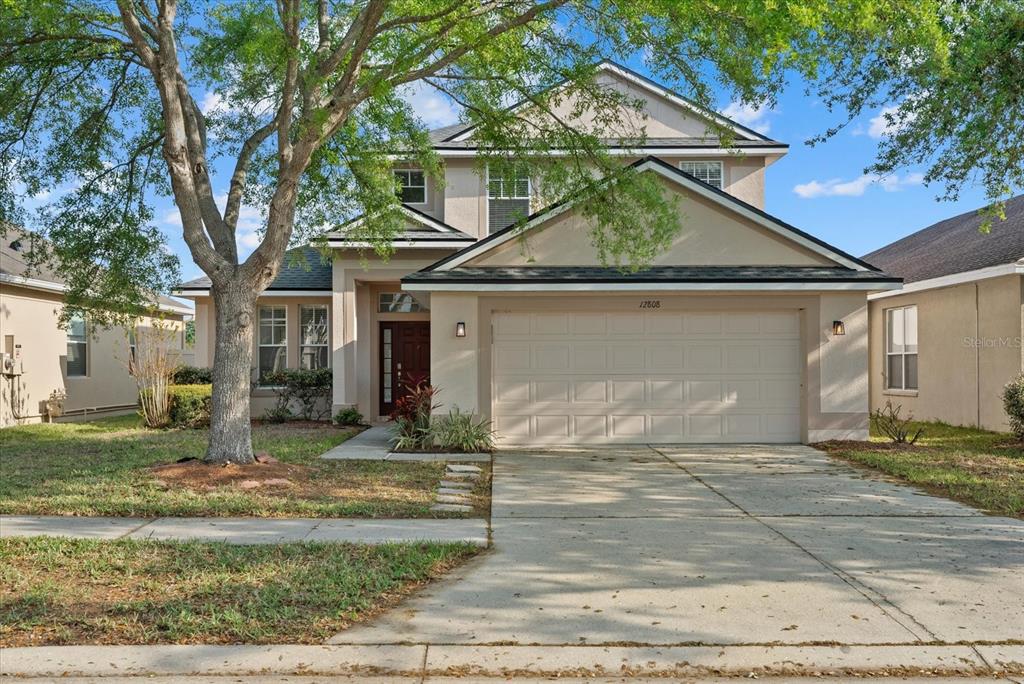 A two-story suburban house with a beige stucco exterior and a two-car garage — 12808 HAMPTON HILL DRIVE, RIVERVIEW, FL