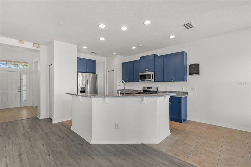 A kitchen features blue cabinets, a granite-topped island, and stainless steel appliances — 12808 HAMPTON HILL DRIVE, RIVERVIEW, FL