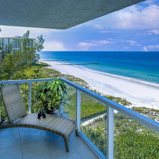 A balcony with a wicker lounge chair overlooks a sandy beach and the ocean — 2425 GULF OF MEXICO DRIVE UNIT 7B, LONGBOAT KEY, FL