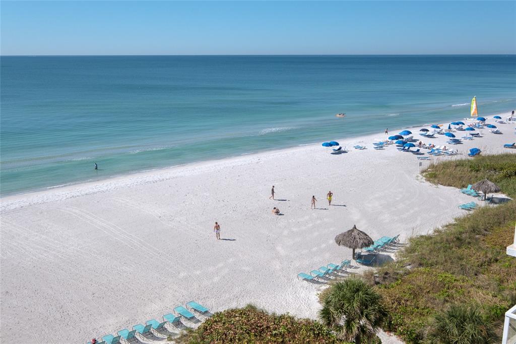 An elevated view of a white sand beach with lounge chairs, umbrellas, and the ocean — 2425 GULF OF MEXICO DRIVE UNIT 7B, LONGBOAT KEY, FL