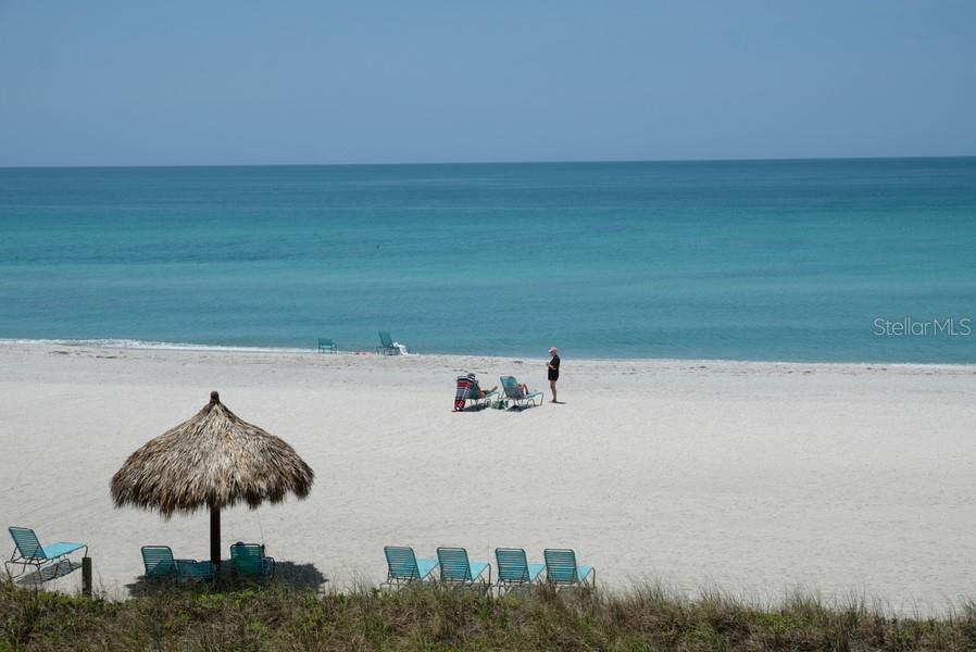 A sandy beach with a tiki umbrella, lounge chairs, and people overlooking the ocean — 2425 GULF OF MEXICO DRIVE UNIT 7B, LONGBOAT KEY, FL