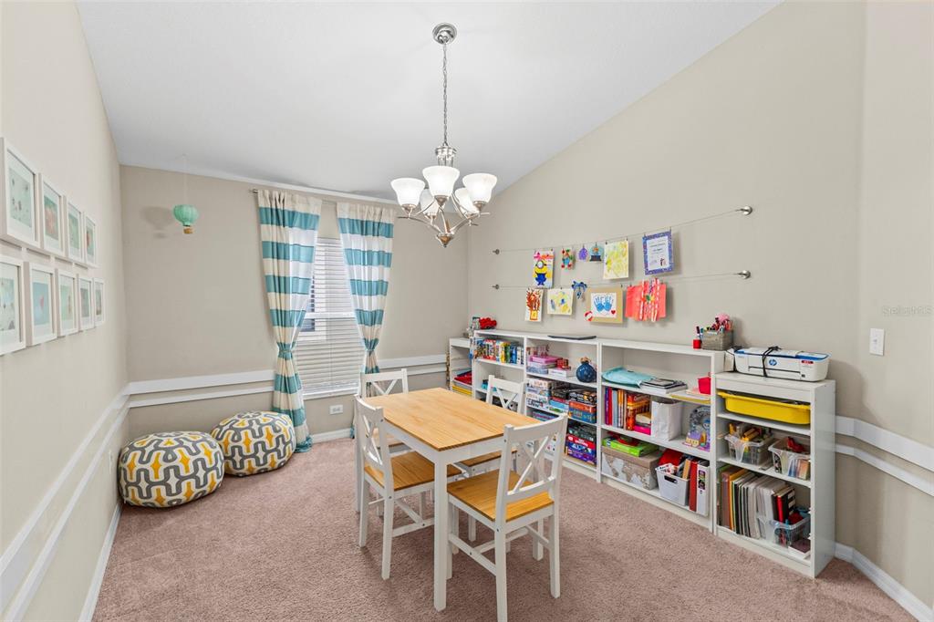 A playroom features a wooden table, white chairs, low shelving units, and wall-mounted artwork displays — 12211 BALLENTRAE FOREST DRIVE, RIVERVIEW, FL