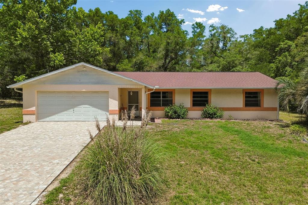 A single-story house with a beige stucco exterior, a two-car garage, and a shingled roof — 3757 E SIDE COURT, INVERNESS, FL