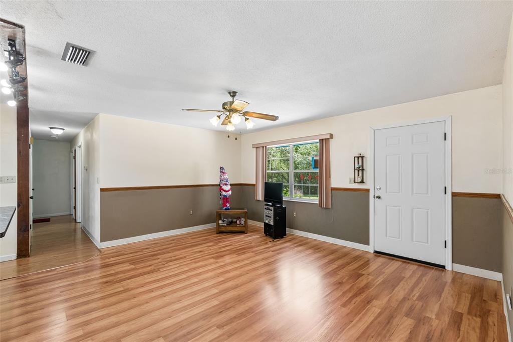 A living room features wood-look flooring, two-tone walls with a chair rail, and a ceiling fan — 3757 E SIDE COURT, INVERNESS, FL
