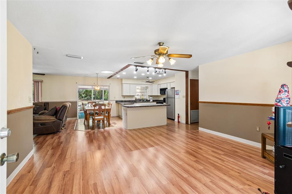 An open-concept living and dining area features wood-look flooring, a kitchen island, and ceiling fans — 3757 E SIDE COURT, INVERNESS, FL