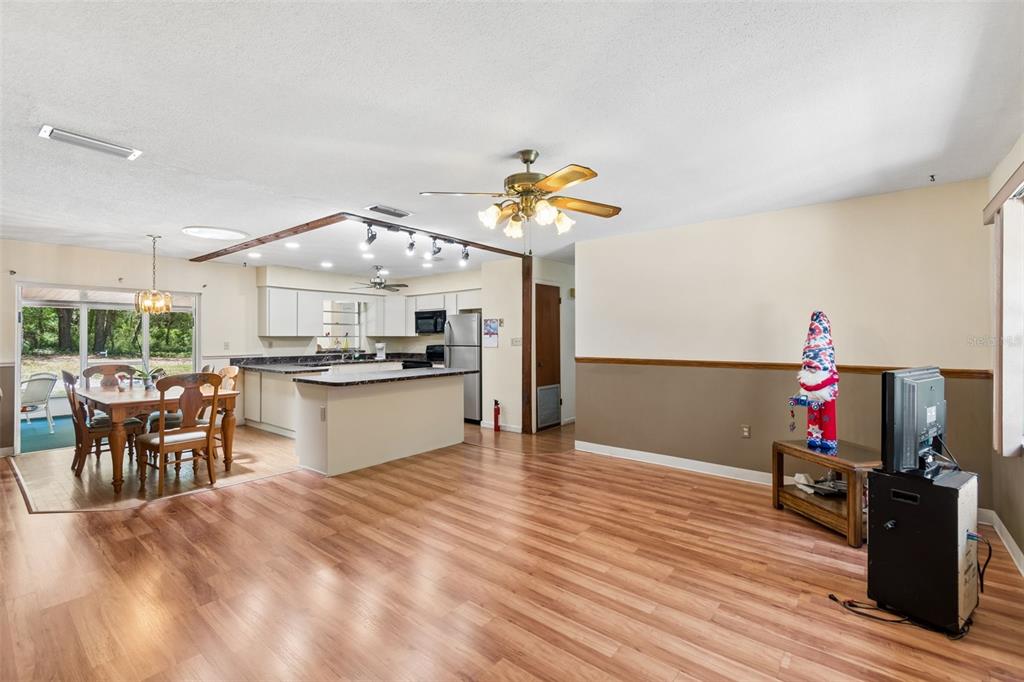 An open-concept living and dining area features wood-look flooring, a kitchen island, and ceiling fans — 3757 E SIDE COURT, INVERNESS, FL