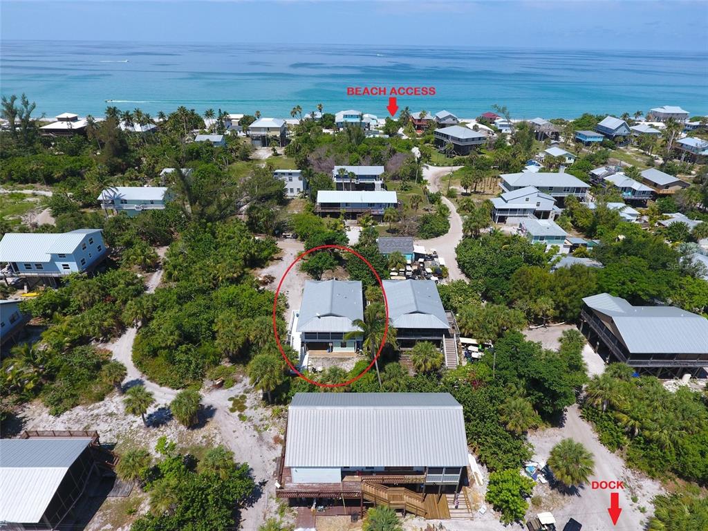 An aerial view shows a coastal neighborhood with houses, dense vegetation, beach access, and a dock — 8662 GRAND AVENUE, PLACIDA, FL