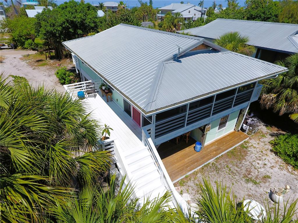 An elevated house with a metal roof, a wrap-around deck, and a wooden ground-level porch — 8662 GRAND AVENUE, PLACIDA, FL