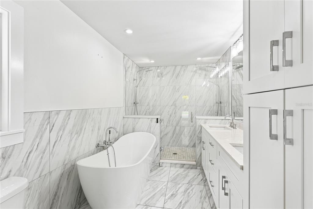 A modern bathroom features a freestanding tub, a glass-enclosed shower, and white marble-style tile — 206 73RD STREET NW, BRADENTON, FL