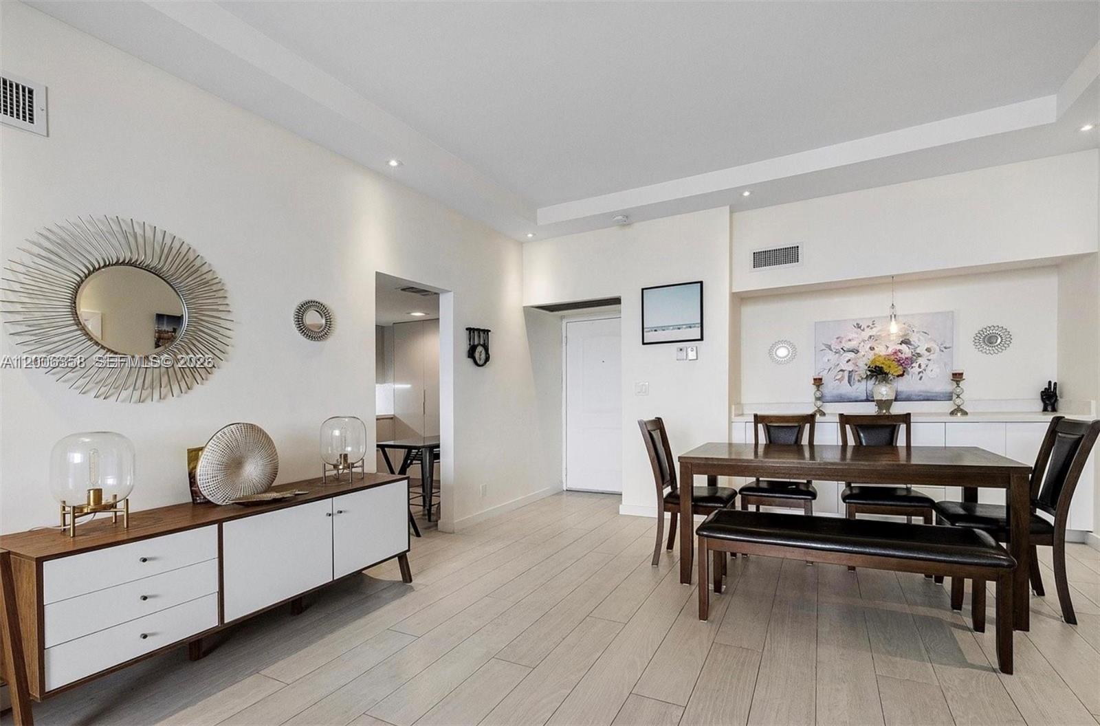 A dining room and living area feature wood-look tile flooring, a sideboard, and a table — 100 bayview dr, Sunny Isles Beach FL 33160, SUNNY ISLES BEACH, FL
