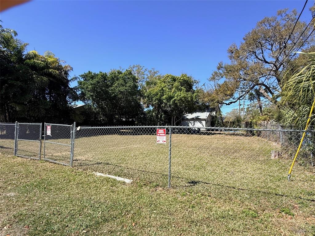 A fenced, vacant grassy lot is surrounded by trees under a clear blue sky — LING-A-MOR TERRACE S, ST PETERSBURG, FL