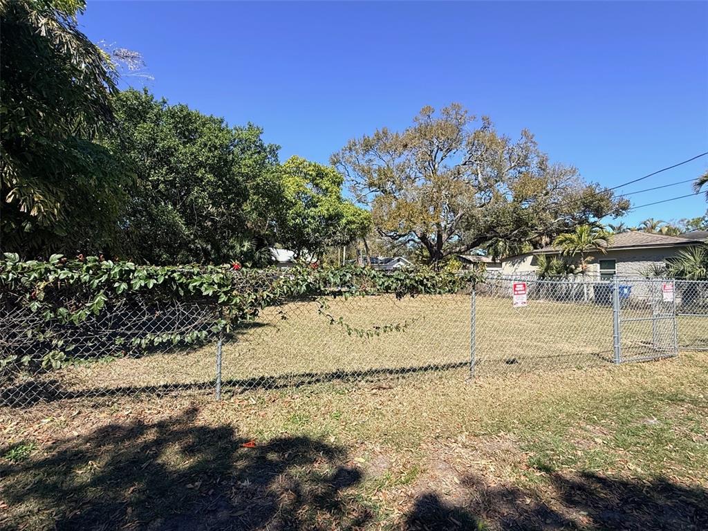 A fenced, grassy vacant lot is surrounded by mature trees and neighboring houses — LING-A-MOR TERRACE S, ST PETERSBURG, FL
