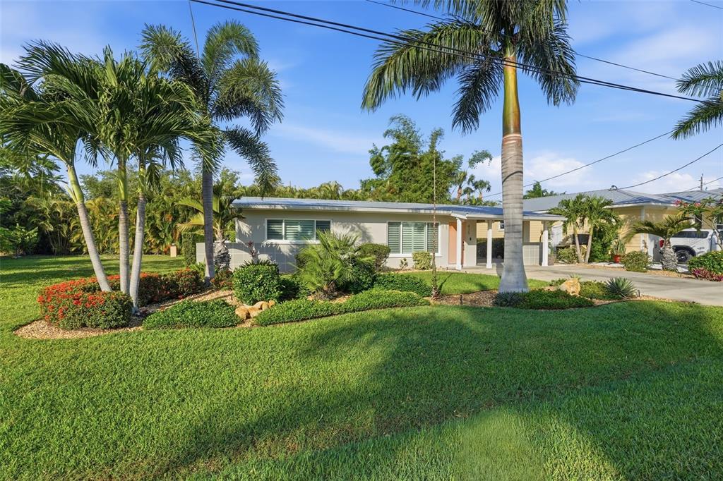 A single-story house with a lawn, palm trees, and a driveway under a blue sky — 415 HARVEY STREET, PUNTA GORDA, FL