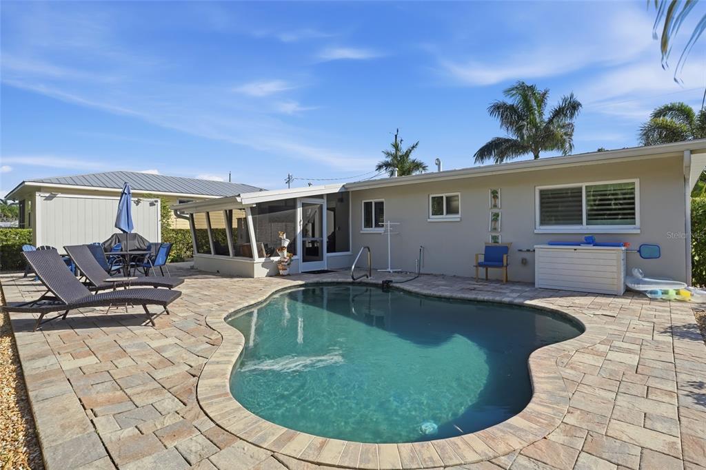 A backyard features a kidney-shaped swimming pool surrounded by a stone paver patio — 415 HARVEY STREET, PUNTA GORDA, FL