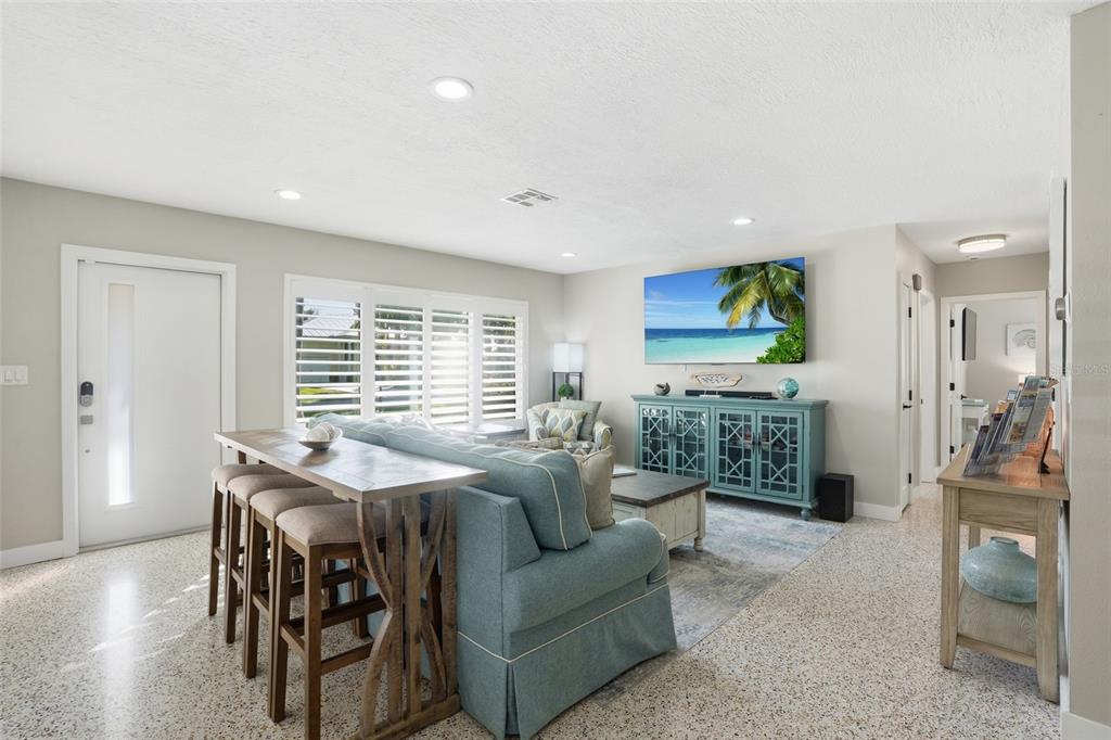A living room features a blue sofa, a console table with stools, and a television — 415 HARVEY STREET, PUNTA GORDA, FL