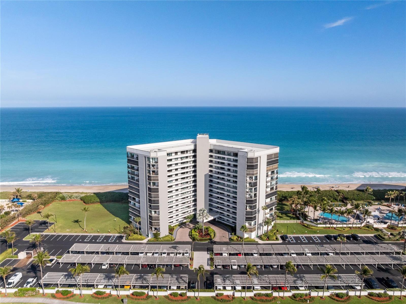 An aerial view of a tall apartment building situated directly on a sandy beach — 8800 S Ocean Drive # 505, Jensen Beach FL 34957, JENSEN BEACH, FL