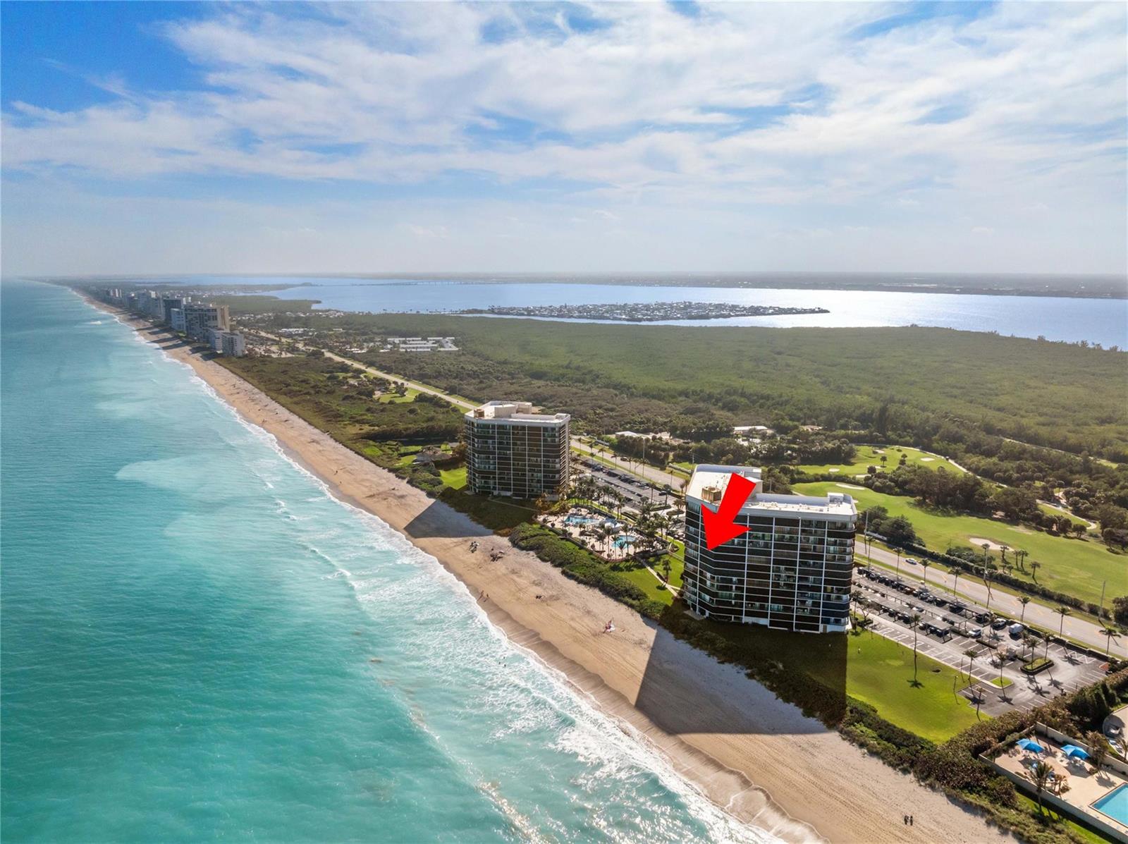 An aerial view of two beachfront high-rise condominiums along a coastline with a red arrow — 8800 S Ocean Drive # 505, Jensen Beach FL 34957, JENSEN BEACH, FL