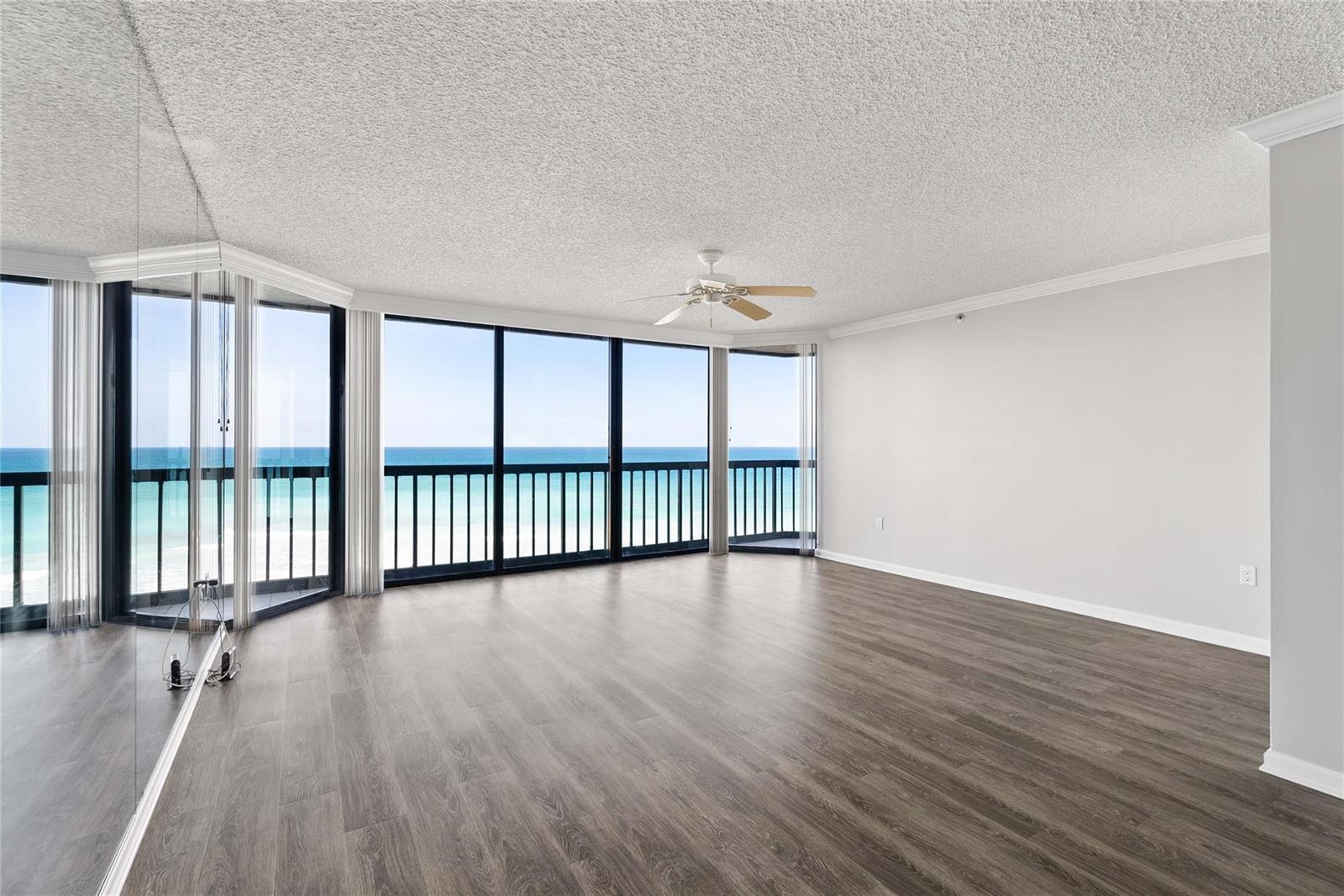 An empty room with wood-look flooring, a ceiling fan, and floor-to-ceiling windows overlooking the ocean — 8800 S Ocean Drive # 505, Jensen Beach FL 34957, JENSEN BEACH, FL