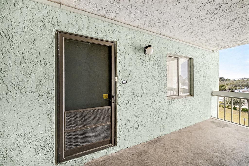 An exterior view of a building hallway featuring a screen door numbered 415 — 801 83RD AVENUE N UNIT 415, ST PETERSBURG, FL