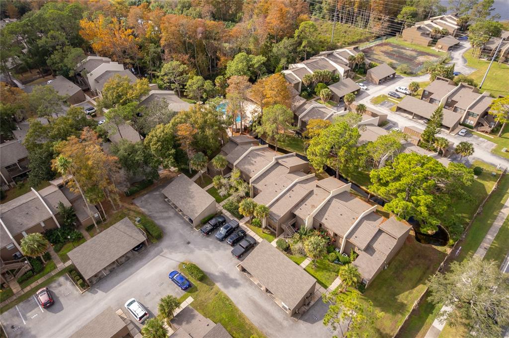 An aerial view shows a multi-unit residential complex with parking lots, trees, and a pool — 4710 JASMINE CREEK LANE UNIT 1506, ORLANDO, FL