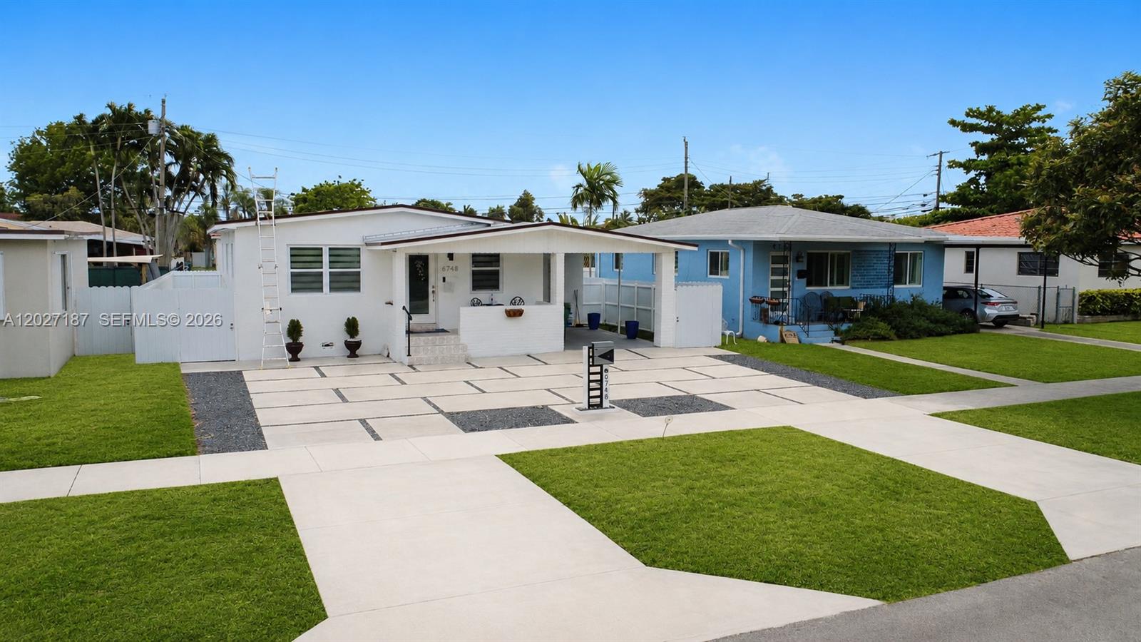 A white house with a carport and a blue house sit side-by-side on a street — 6748 SW 38th St, Miami FL 33155, MIAMI, FL