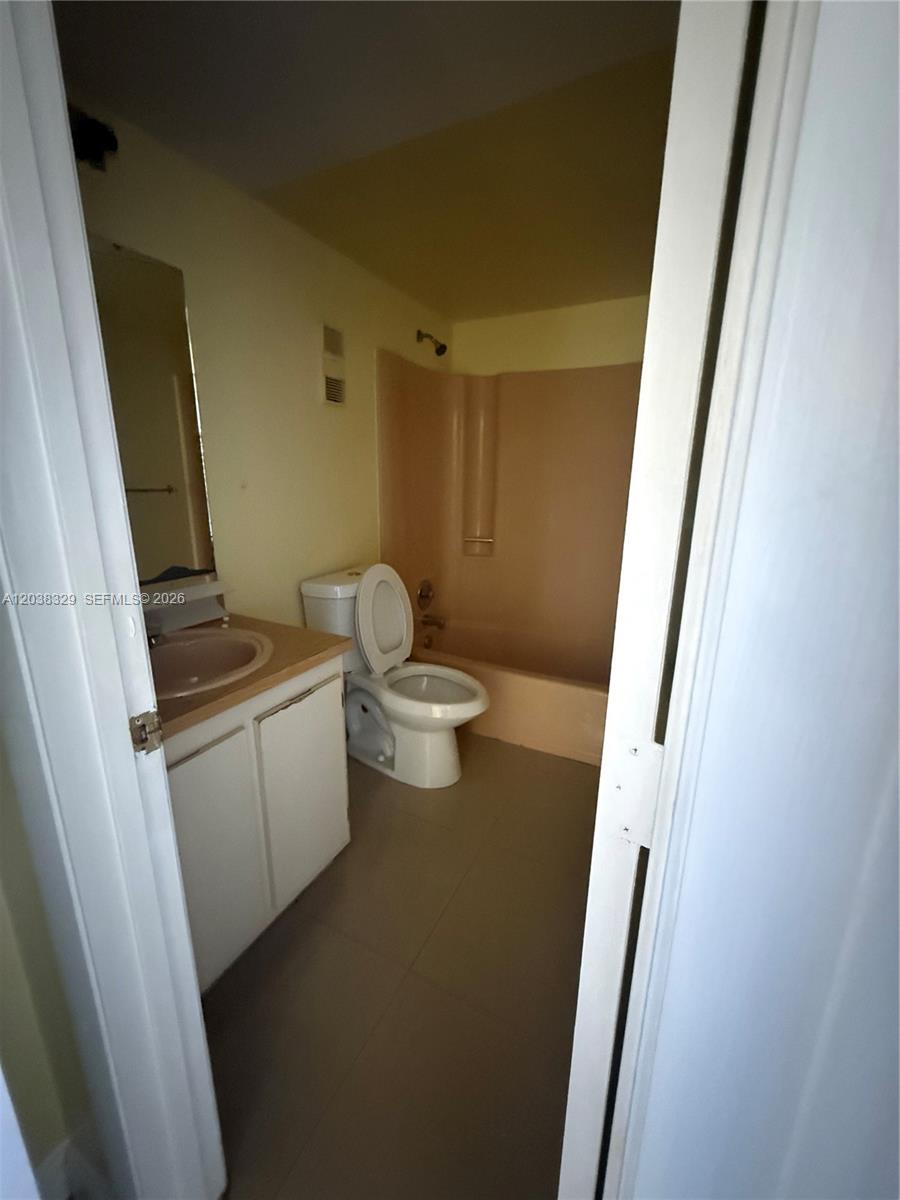 A bathroom features a vanity with a pink sink, a white toilet, and a bathtub — 8740 N Sherman Cir # 402, Miramar FL 33025, MIRAMAR, FL