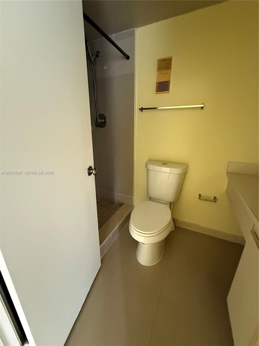 A bathroom features a white toilet, a walk-in shower, and a vanity counter — 8740 N Sherman Cir # 402, Miramar FL 33025, MIRAMAR, FL