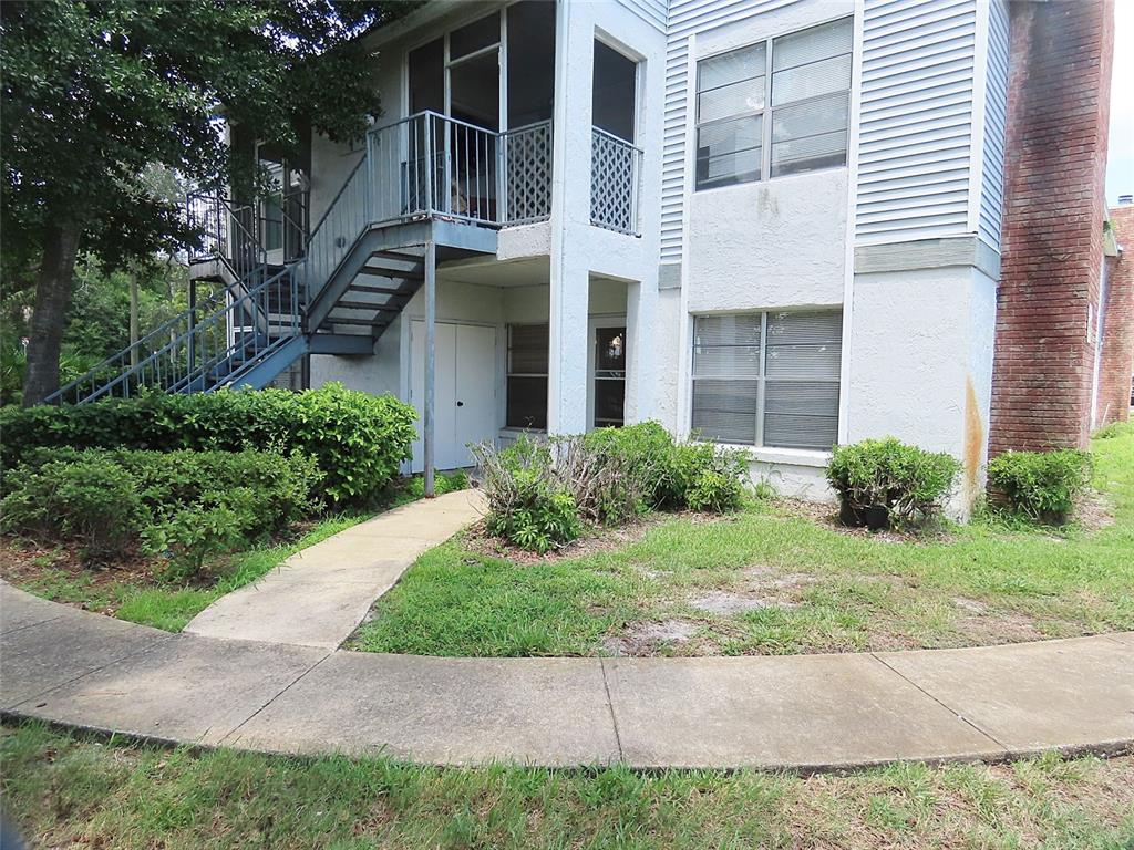 A two-story apartment building with a metal staircase, screened balcony, and a brick chimney — 104 NORTHLAKE DRIVE UNIT 104, SANFORD, FL
