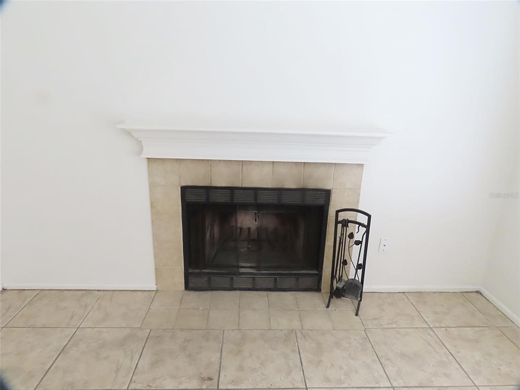 A fireplace with a white mantel and tan tile surround sits on a tiled floor — 104 NORTHLAKE DRIVE UNIT 104, SANFORD, FL