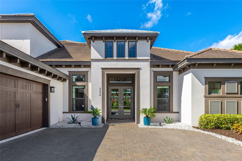 The exterior of a modern house features a paved driveway, double front doors, and landscaping — 8232 SUMMER NIGHT ROAD, SARASOTA, FL