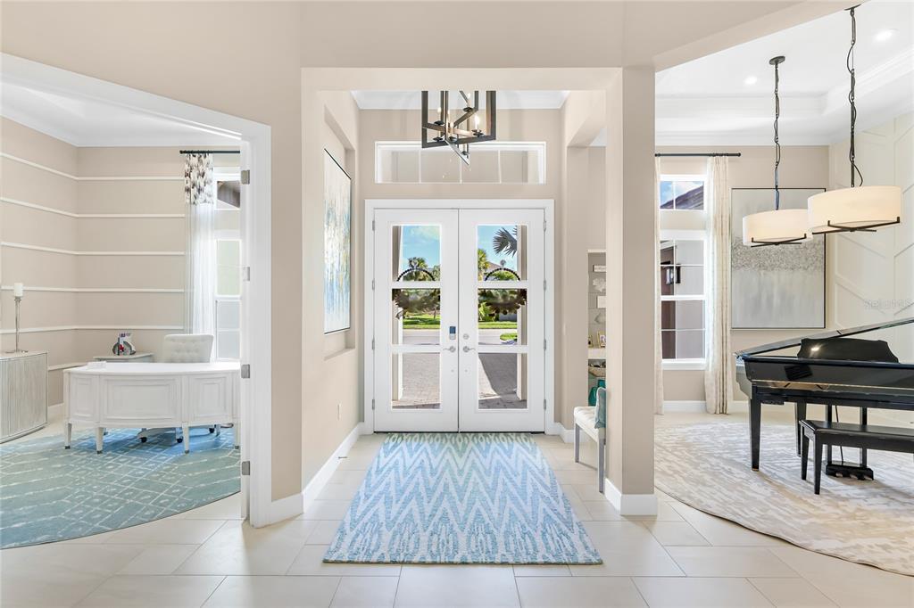 A bright foyer features double glass front doors, a patterned rug, and adjacent living spaces — 8232 SUMMER NIGHT ROAD, SARASOTA, FL
