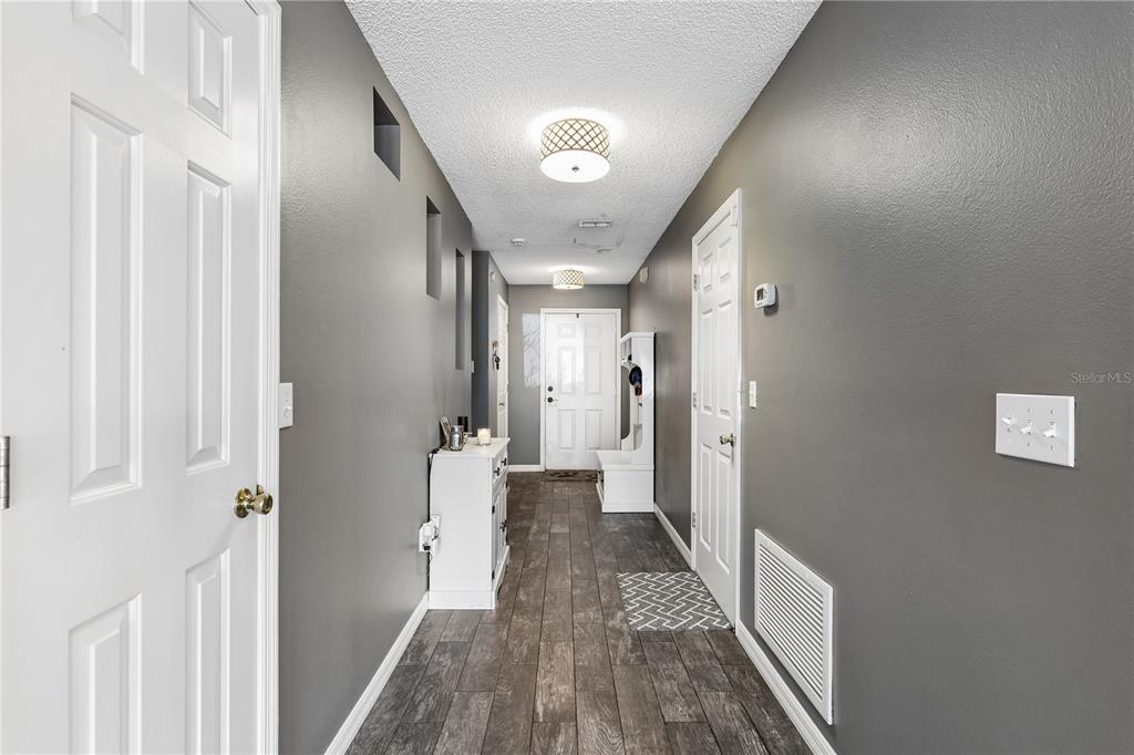 A hallway with gray walls, wood-look flooring, white trim, and two drum-style ceiling lights — 1210 N FAIRWAY DRIVE UNIT 1210, APOPKA, FL