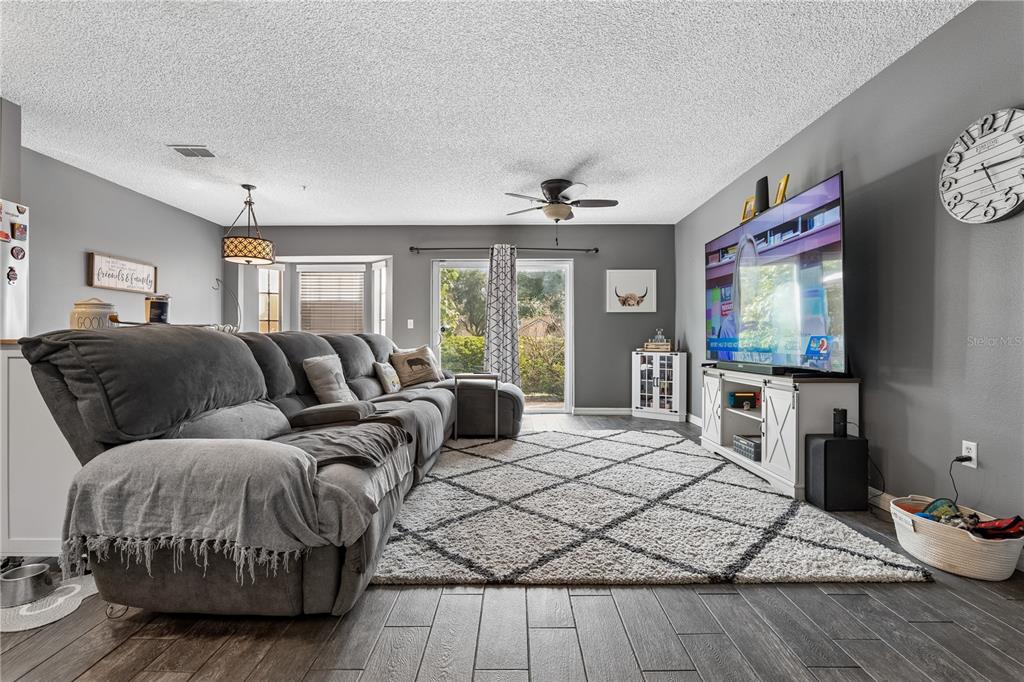 A living room features a grey sectional sofa, a large area rug, and a television console — 1210 N FAIRWAY DRIVE UNIT 1210, APOPKA, FL