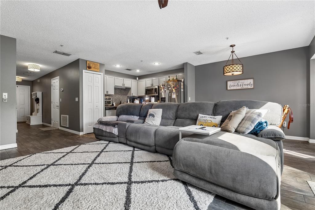 A gray sectional sofa sits on a patterned rug in a living room with gray walls — 1210 N FAIRWAY DRIVE UNIT 1210, APOPKA, FL