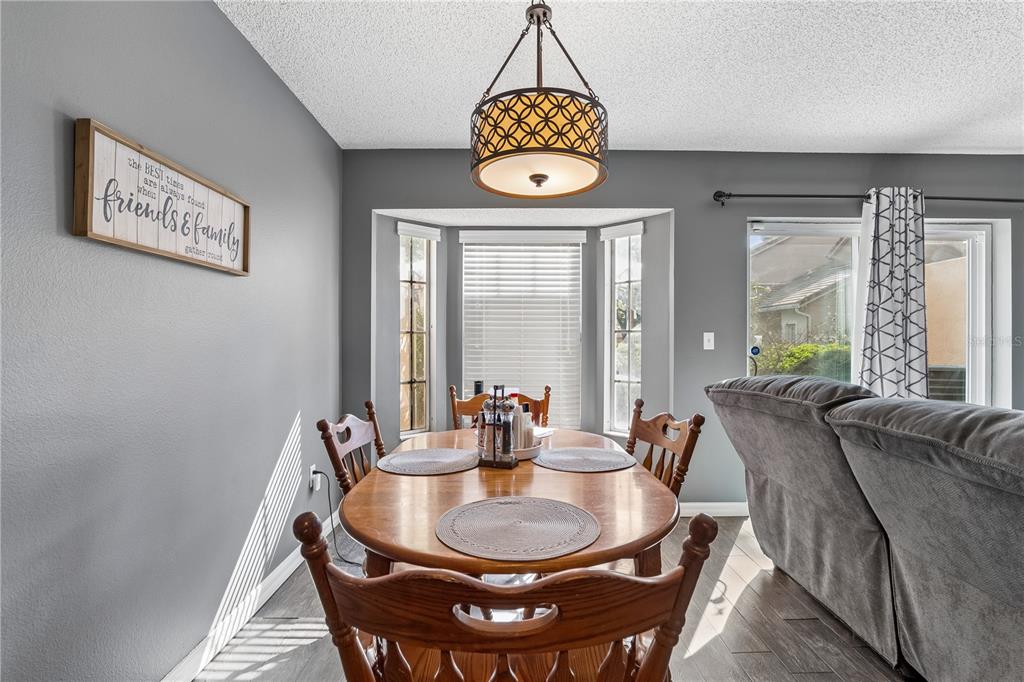 A dining area features a wooden table, chairs, a pendant light, and gray walls — 1210 N FAIRWAY DRIVE UNIT 1210, APOPKA, FL