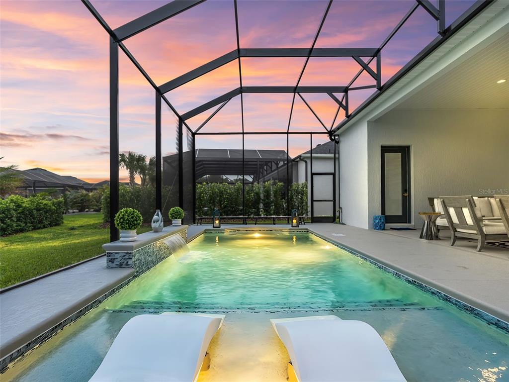 A screened-in patio features a swimming pool with a sun shelf and a water feature — 7095 JENNINGS COURT, THE VILLAGES, FL