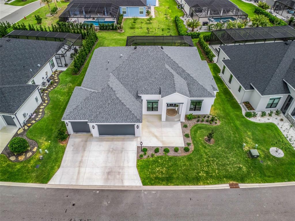 An aerial view shows a single-story house with a gray roof and a concrete driveway — 7095 JENNINGS COURT, THE VILLAGES, FL