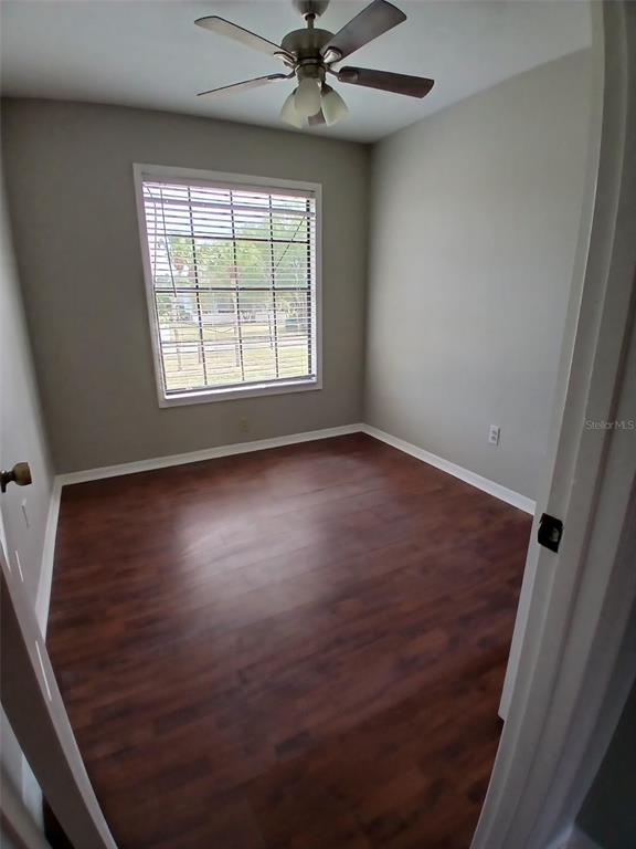 An empty bedroom features wood-look flooring, light gray walls, a ceiling fan, and a window — 7454 WYNNEWOOD SQUARE UNIT 188, WINTER PARK, FL