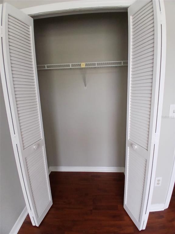 A closet with white louvered doors, a wire shelf, and dark wood-look flooring — 7454 WYNNEWOOD SQUARE UNIT 188, WINTER PARK, FL